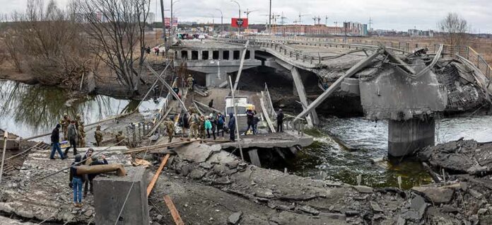 shutterstock_2133513579 People crossing a destroyed concrete bridge over a river