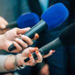 License Loopholes Kill — Senator Demands Answers Reporters holding colorful microphones