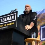 Media Rushes Judgment — Facts Still Unchecked Speaker at outdoor podium with campaign signs