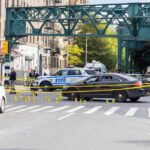 Upscale Zip Code, Unthinkable Violence Police cars block a city intersection with yellow crime scene tape