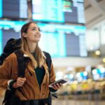 America 250 Snub—NYC First Lady Bolts traveler with backpack checking flight information boards
