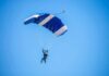 Skydiver descending under a blue parachute