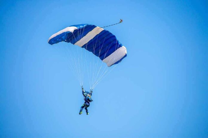 Skydiver descending under a blue parachute