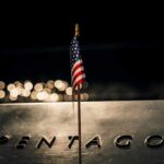 Small American flag on a memorial with bokeh lights at night