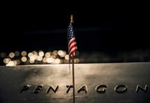 Small American flag on a memorial with bokeh lights at night