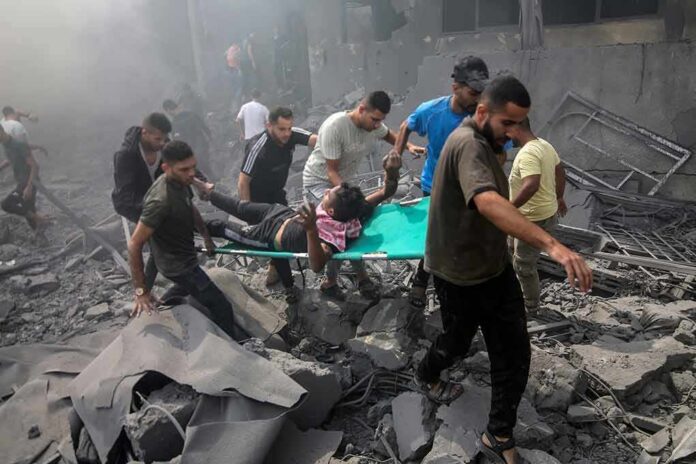 shutterstock_2374212961 Rescuers carry an injured person on a stretcher through rubble