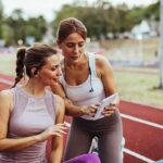 This Women’s Sports Number Is Turning Heads Two women at a running track looking at a tablet