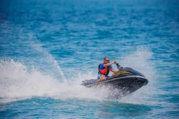 shutterstock_255572965 Man riding a jet ski across blue ocean water