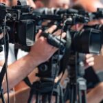 Deadlock Drama: Court Walks a Razor television cameras on tripods at a media event