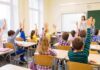 Parents Want Answers About 9/11 Lessons Students raise hands in a classroom while a teacher stands at the front