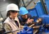 workers operating a metal lathe in a workshop