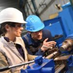 workers operating a metal lathe in a workshop
