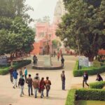 courtyard with statue and people near a pink temple