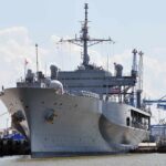 Navy Still Feeling Effects Of Iran’s Bahrain Strike Large gray naval ship docked at an industrial port