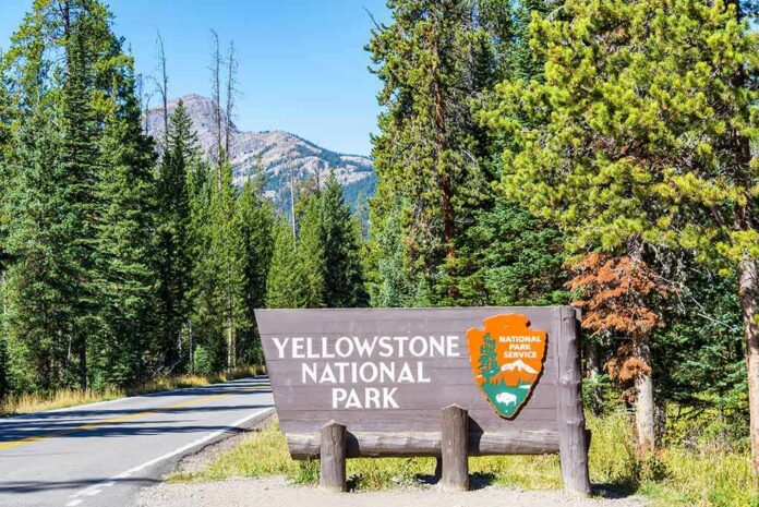 shutterstock_458781274 Yellowstone National Park entrance sign by forest road