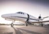 Private jet on airport tarmac with open door at sunset