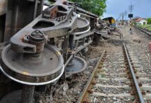 Overturned train cars beside railway tracks