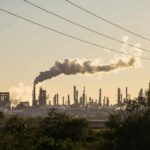 A Major Oil Refinery Comes Under Drone Attack Industrial refinery with smokestack emitting plume at sunset