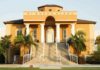 Fraternity house with columns and palm trees in front