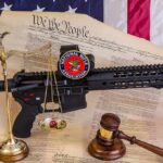 Rifle with NRA badge on Constitution backdrop with scales and gavel