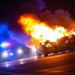 Burning car on a dark street at night