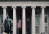 Trump Checks Land – 1M Get $500 Statue in front of a neoclassical government building with columns and a U.S. flag