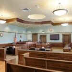 Officer Loses Eye – System Finally Bites Back Empty courtroom with wooden benches and judge's bench
