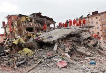 State of Emergency After Back-to-Back Quakes Rescue workers in orange uniforms on a collapsed building site after an earthquake
