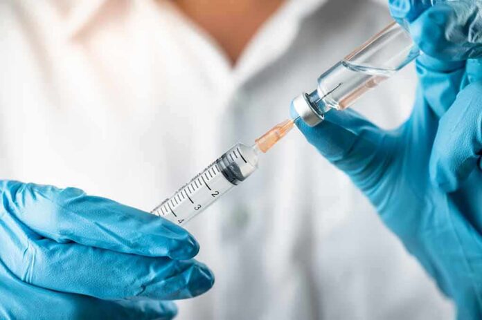 shutterstock_1506051596 Gloved hands drawing liquid into a syringe from a vial