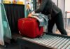 Red suitcase on airport security conveyor belt