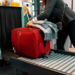 Red suitcase on airport security conveyor belt