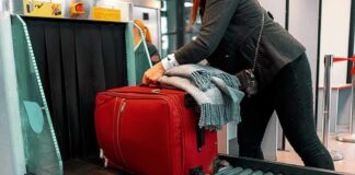 Red suitcase on airport security conveyor belt