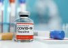 COVID-19 vaccine vial with test tube on lab bench