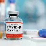 Payouts Expose Canada’s Vaccine Dilemma COVID-19 vaccine vial with test tube on lab bench