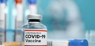 COVID-19 vaccine vial with test tube on lab bench