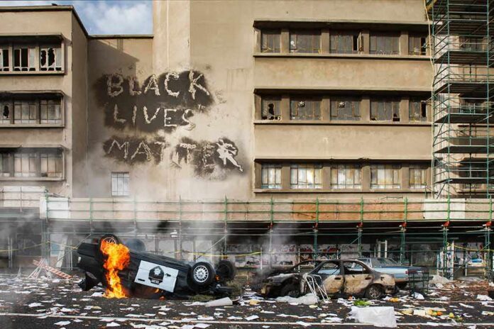 shutterstock_1752732488 Burning overturned police car in front of a damaged building