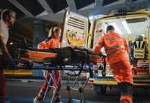 Paramedics load a patient on a stretcher into an ambulance at night