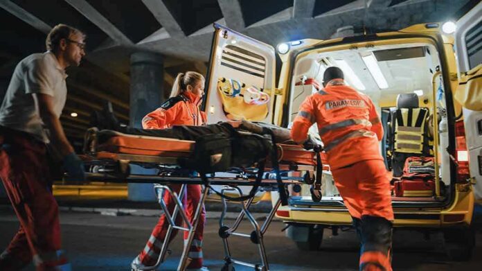 Paramedics load a patient on a stretcher into an ambulance at night