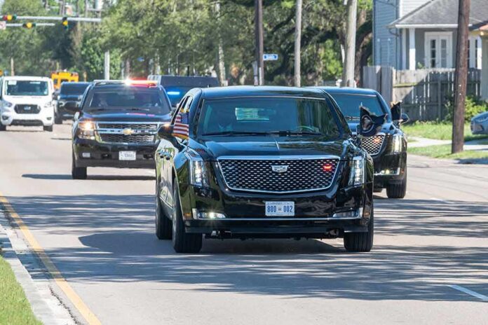 Motorcade of black SUVs and sedans driving down a city street