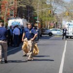 Police officers and investigators at a blocked city street scene