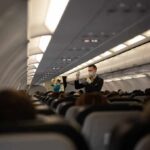 Flight attendant demonstrates safety procedures in airplane cabin