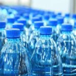 Plastic water bottles with blue caps in rows