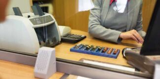 Bank teller at counter handling cash and coins