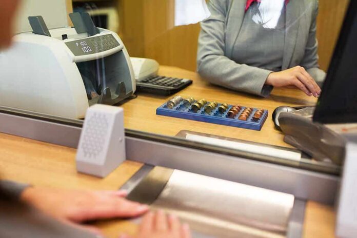 Bank teller at counter handling cash and coins