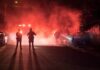 Halloween Celebration Erupts in Gunfire Police officers watch firefighters extinguish a car fire at night