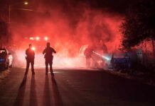 Halloween Celebration Erupts in Gunfire Police officers watch firefighters extinguish a car fire at night