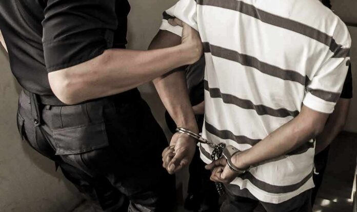 shutterstock_741919558 person in handcuffs escorted by an officer